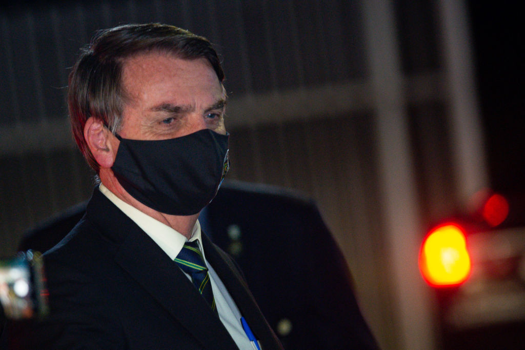 President of Brazil Jair Bolsonaro, wearing a face mask with a print of Brazil's Coat of Arms and written God above all, Brazil above all, reacts to supporters of his government who waited for him outside the Palácio do Alvorada amidst the coronavirus (COVID-19) pandemic on May 27, 2020 in Brasilia.